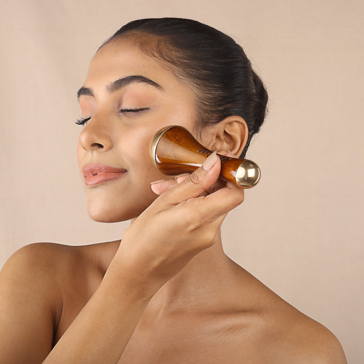 Woman using Art of Vedas Kansa wand for Ayurvedic facial massage - bronze and wood face massage tool for skin rejuvenation and Marma therapy