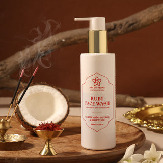 A high-resolution image displaying Art of Vedas Ruby Face Wash. The product is housed in an elegant, amber-colored bottle with a pump dispenser, highlighted against a clean, white background. The label is clearly visible, featuring intricate, traditional